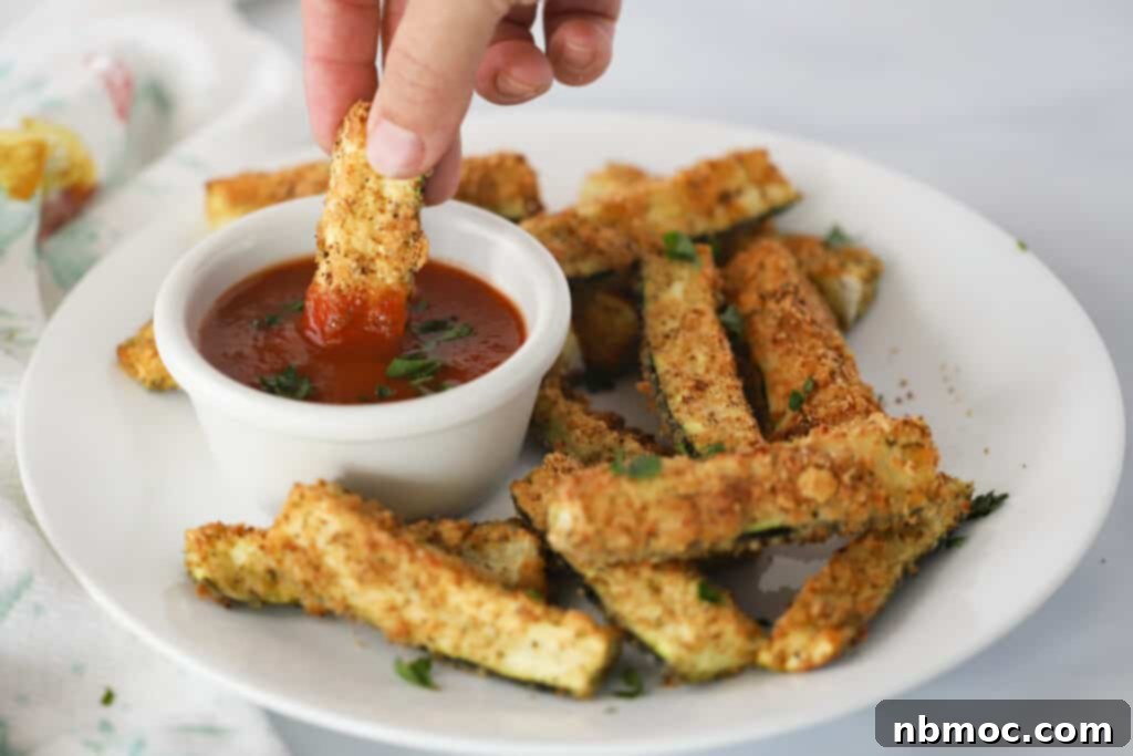 Crispy Zucchini Fries 3 A serving plate full of baked Parmesan Zucchini Fries with a side ramekin of marinara sauce, ready to be enjoyed.