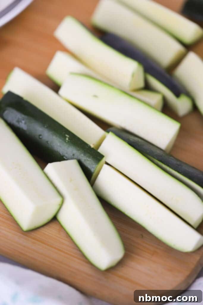 Crispy Zucchini Fries 4 A cutting board with fresh zucchini cut into spears, ready for breading.