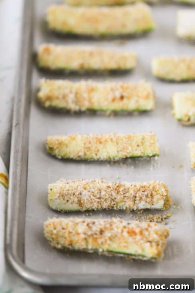 Crispy Zucchini Fries 6 A sheet tray lined with parchment paper that has zucchini sticks lined up, perfectly spaced out.