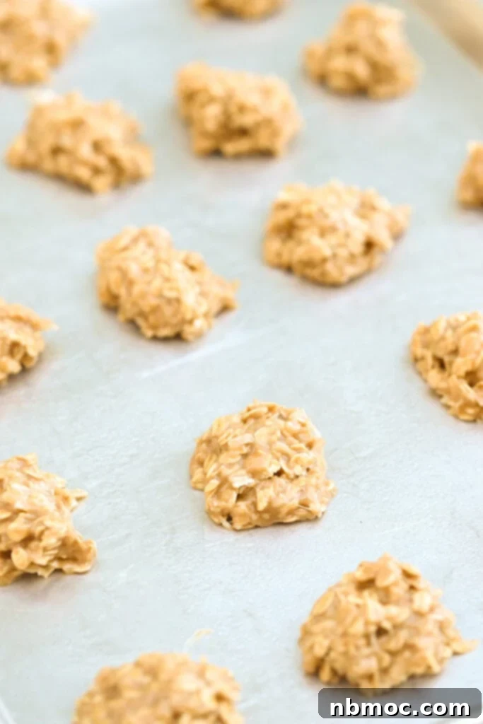 No bake peanut butter and coconut cookies spread out on a baking sheet. 
