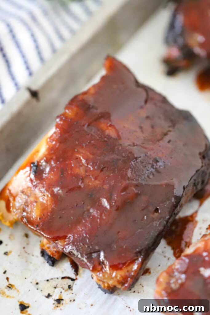 Slow cooker pork spare ribs covered in barbecue sauce on a baking sheet.