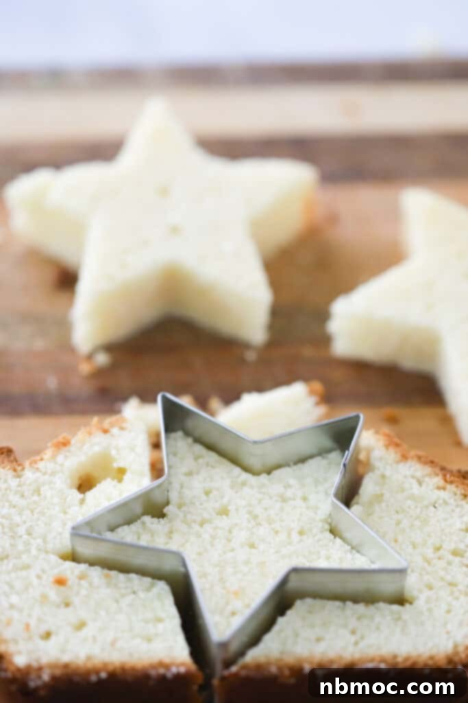 Pound cake cut into festive star shapes on a wooden cutting board, ready for a berry trifle.