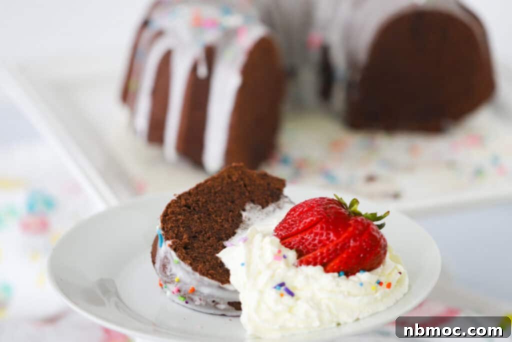 Decadent Chocolate Pound Cake 3 A delectable slice of chocolate cream cheese pound cake presented on a pristine white serving plate, adorned with a sweet glaze, colorful sprinkles, a dollop of whipped cream, and a fresh strawberry, illustrating ideal chocolate pound cake recipes.