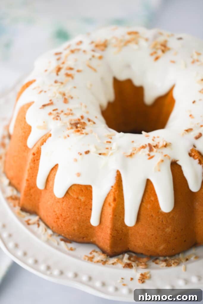 A serving plate with a large Coconut Pound Cake topped with white glaze and toasted coconut. Coconut bundt cake.