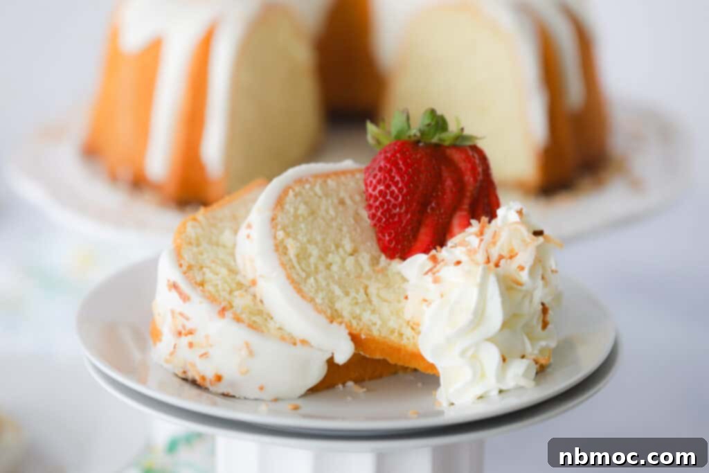 A plate with two slices of Coconut Pound Cake with a white glaze and topped with whipped cream and strawberries, coconut pound cake recipes.