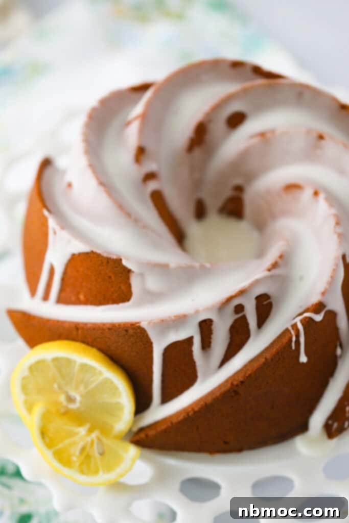 A glazed Lemon Cream Cheese Pound Cake on a cake stand, ready to be served.