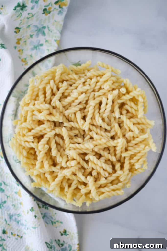 Ultimate BLT Pasta Salad 4 A large glass bowl full of cooked spiral pasta noodles.