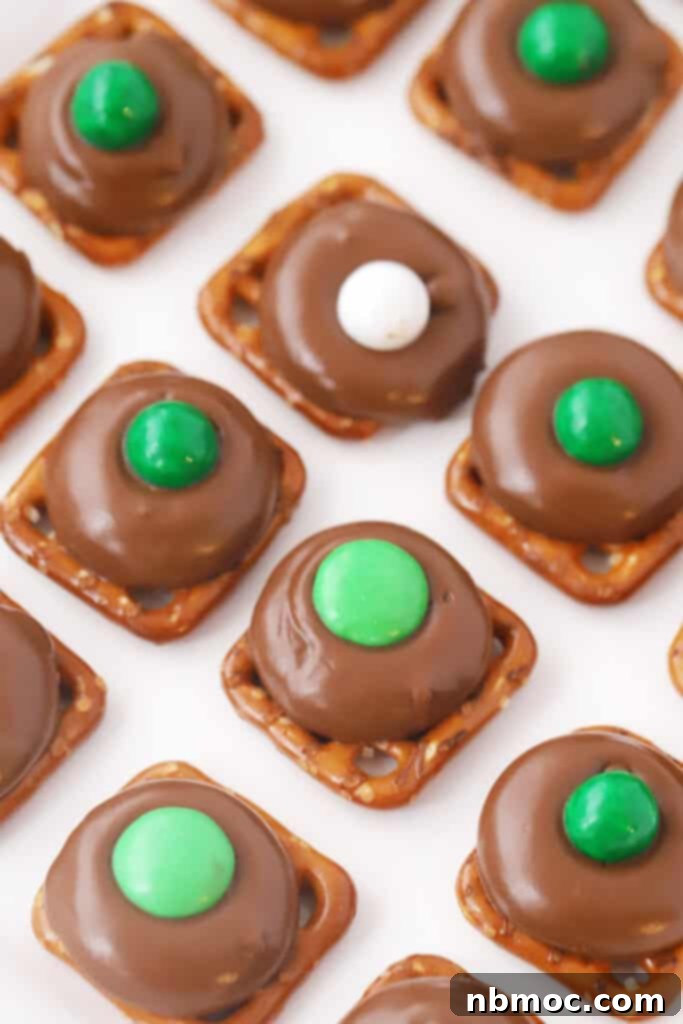 21+ Decadent Caramel Dessert Recipes 14 A tray filled with homemade candies, featuring pretzels topped with Rolos and decorated with colorful chocolate candies.