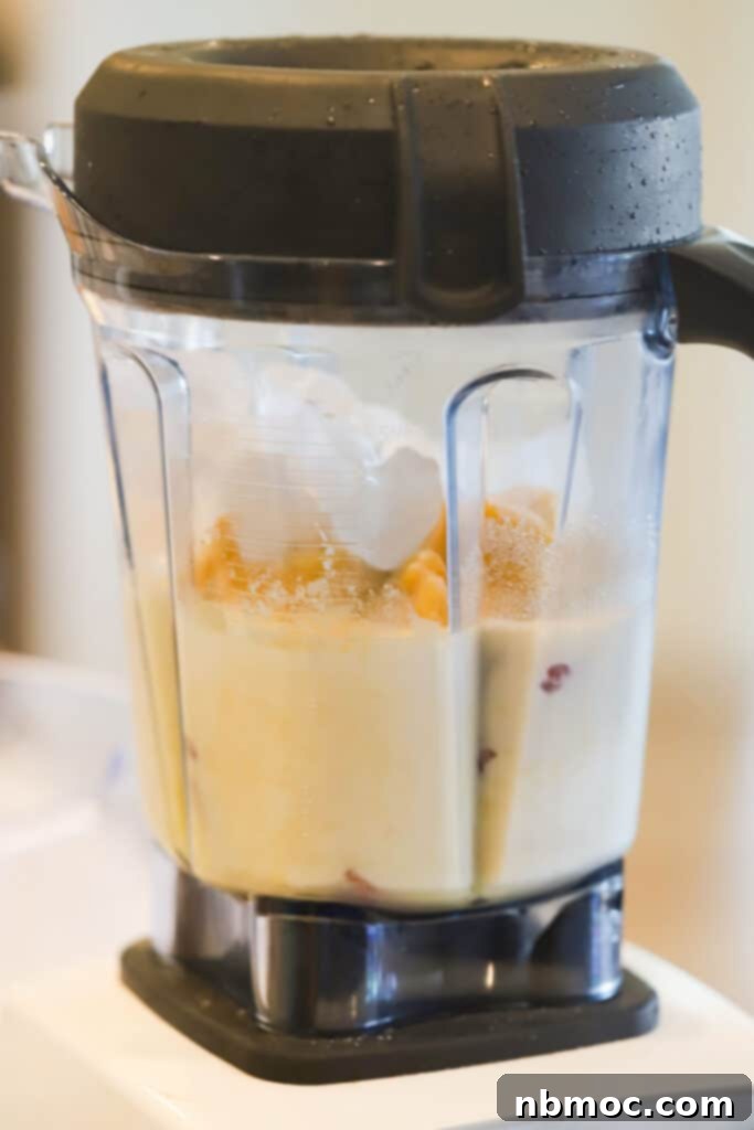 Creamy Citrus Berry Swirl 4 A side view of a blender filled with ingredients to make this Strawberry Orange Julius recipe.