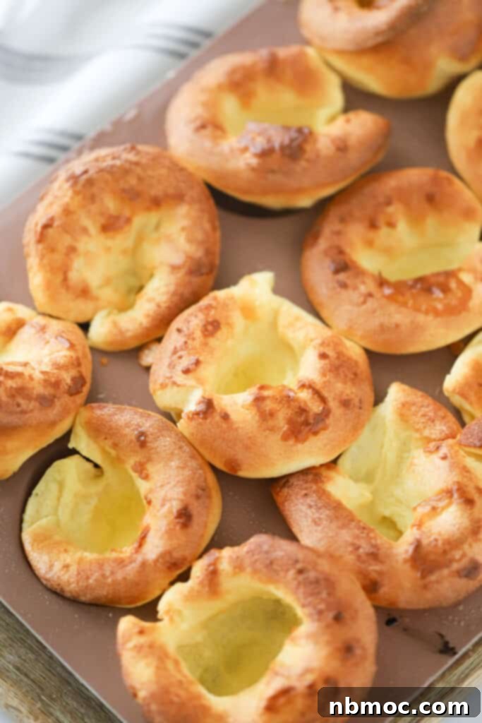 Oven-Puffed Golden Wonders 2 Rows of golden, perfectly risen popovers on a baking sheet, showcasing their fluffy texture.