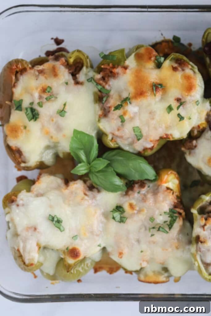 Easy Stuffed Peppers recipe topped with melted cheese and fresh basil in a baking dish. 