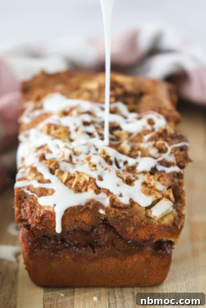 A beautifully glazed Apple loaf cake with glaze being drizzled over the top, ready to be served.