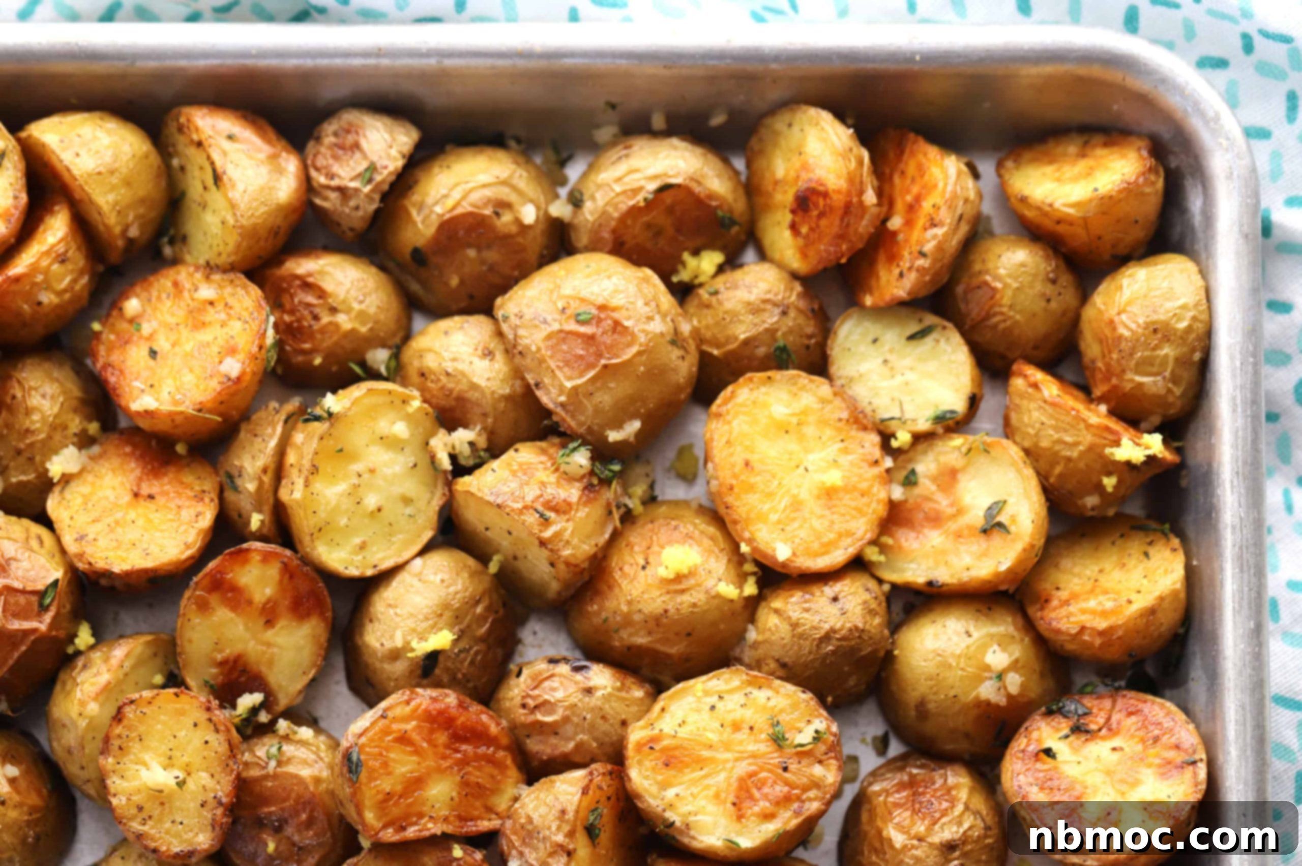 Golden brown and aromatic Herb Roasted Potatoes baking on a sheet pan in the oven, nearly ready to serve.