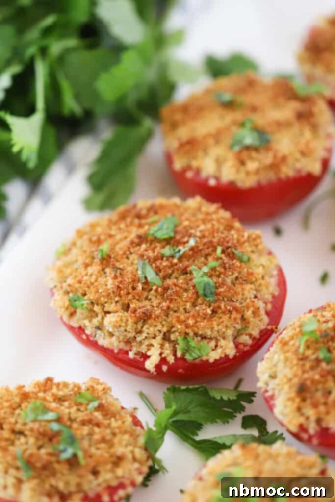 A serving platter full of baked tomatoes with Parmesan and panko crust.