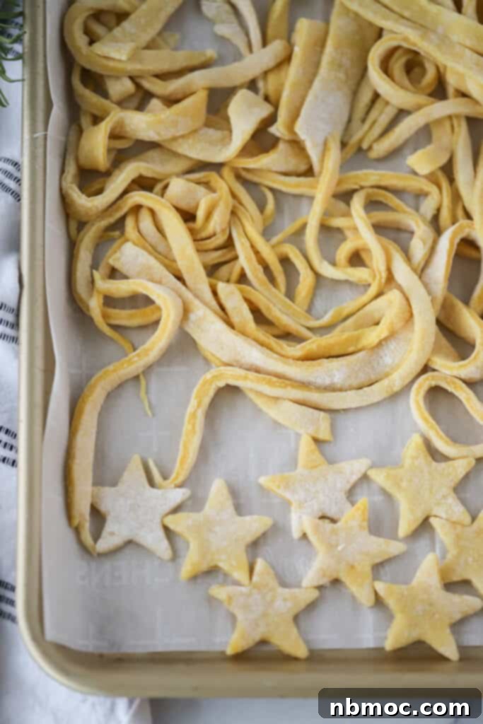 Golden Egg Noodles 2 Homemade egg noodles on a baking sheet cut into long pieces and star shapes, ready to be cooked or dried.