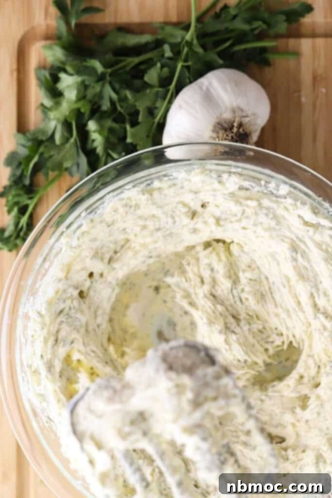 Artisan Garlic Butter 2 A hand mixer whipping garlic butter spread in a clear glass bowl, showcasing its creamy texture.