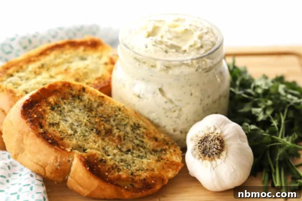 Artisan Garlic Butter 4 A jar full of homemade garlic butter spread recipe, next to golden garlic bread slices on a wooden cutting board.
