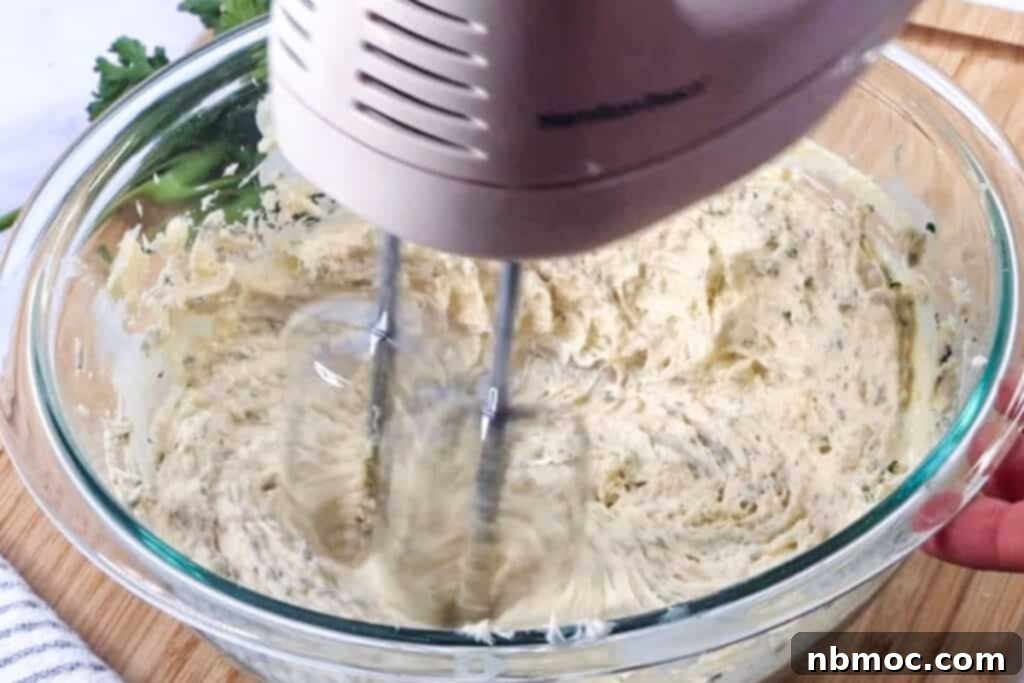 Artisan Garlic Butter 5 A close-up of butter being whipped with a hand mixer in a glass bowl, creating a smooth garlic spread.