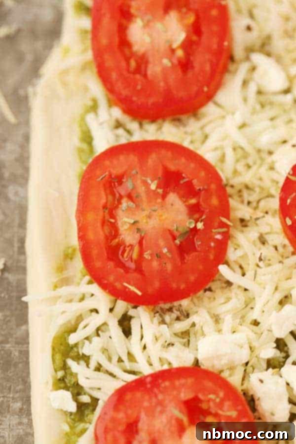 Delicious Pesto Flatbread with fresh tomatoes and three kinds of cheese, ready to serve.