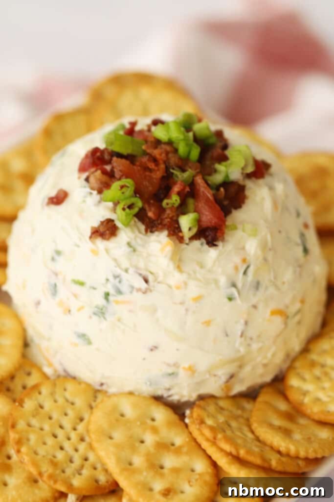 A savory bacon cheddar cheese ball, generously topped with crispy bacon bits and sliced scallions, nestled among golden Ritz crackers for an enticing appetizer display.
