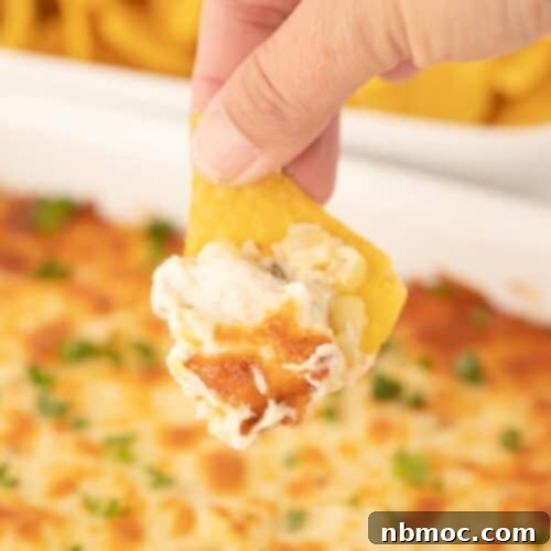 Vibrant Fiesta Corn Dip 5 Easy Fiesta Corn Dip in a baking dish with a hand dipping a chip into it.