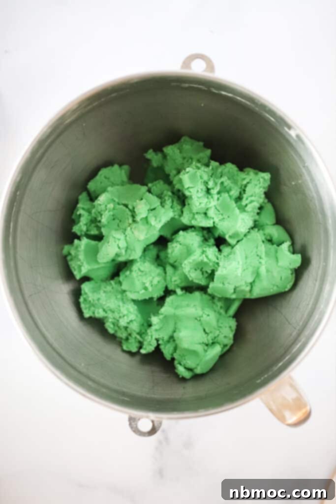 Green Mean Christmas Treats 3 A mixing bowl filled with vibrant green cookie dough, ready to be scooped and baked into festive Grinch Cookies.