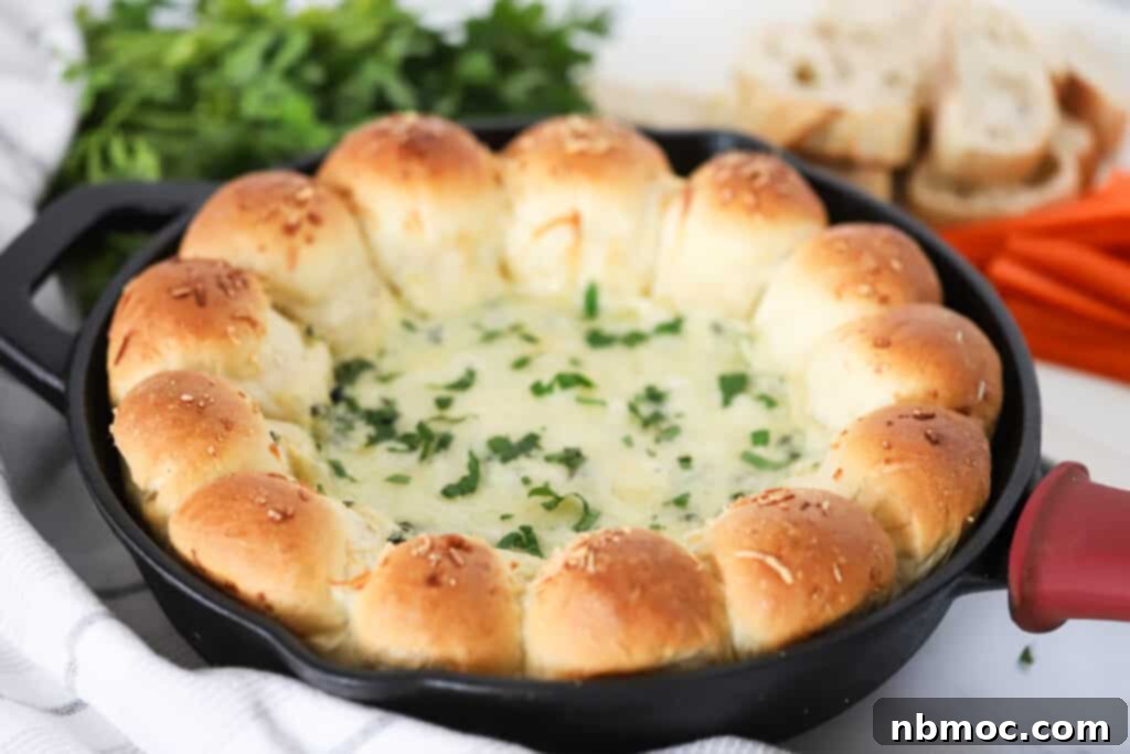 A cast iron skillet with a golden brown Spinach Dip Bread Ring, featuring soft garlic rolls encircling a bubbling cheese and spinach dip.