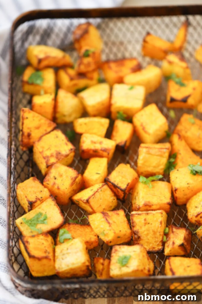 An air fryer basket full of Air Fryer Squash cubes; air fryer acorn squash; acorn squash air fryer; how to cook squash in air fryer.