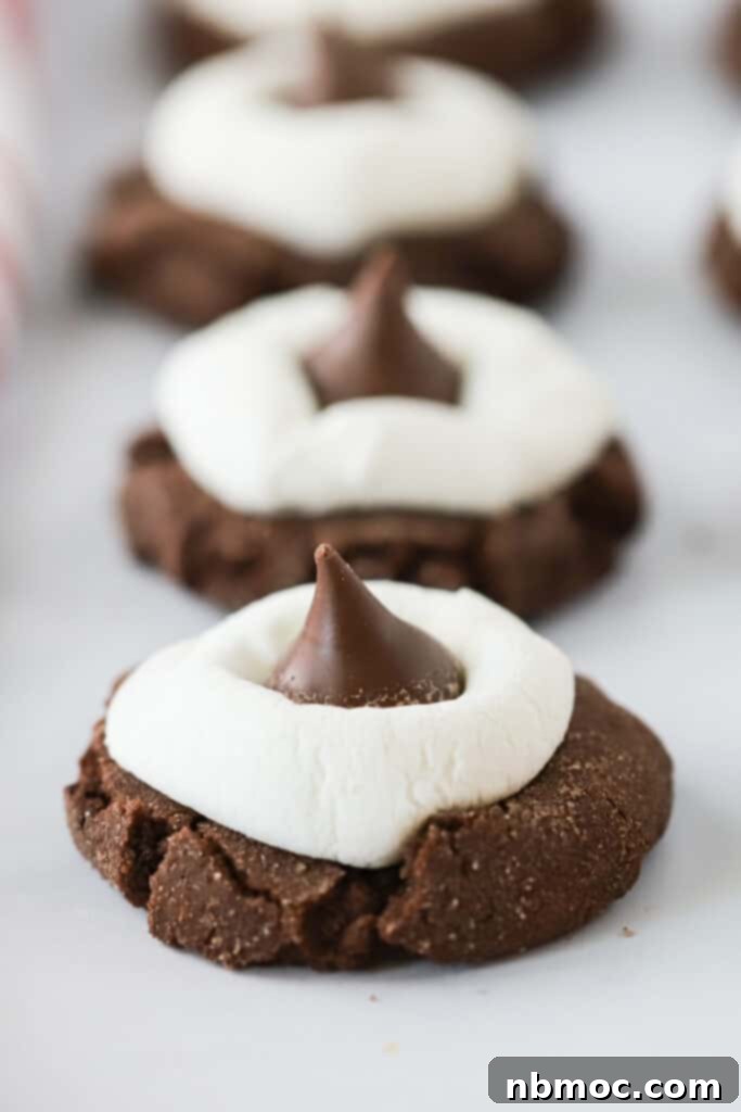 A row of Hot Chocolate Kiss Cookies topped with marshmallows and Hershey's Kisses. hot cocoa kisses, hot chocolate hershey kisses. chocolate kisses cookies. 