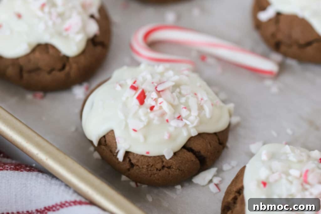 A full baking sheet showcasing beautifully iced Peppermint Meltaway Cookies, topped with crushed candy canes, ready for holiday festivities. This is the ultimate mint meltaway cookie recipe.