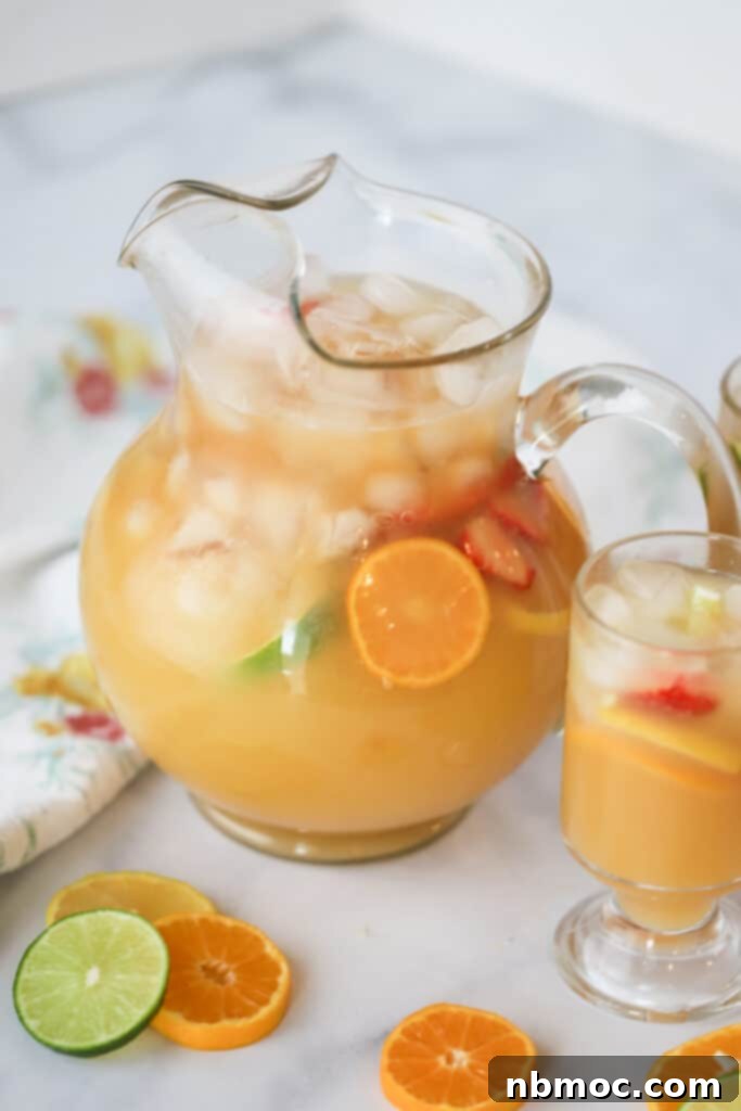 Exotic Fruit Fusion 4 A large pitcher of bright tropical punch, brimming with fresh fruit and ice, surrounded by citrus slices.