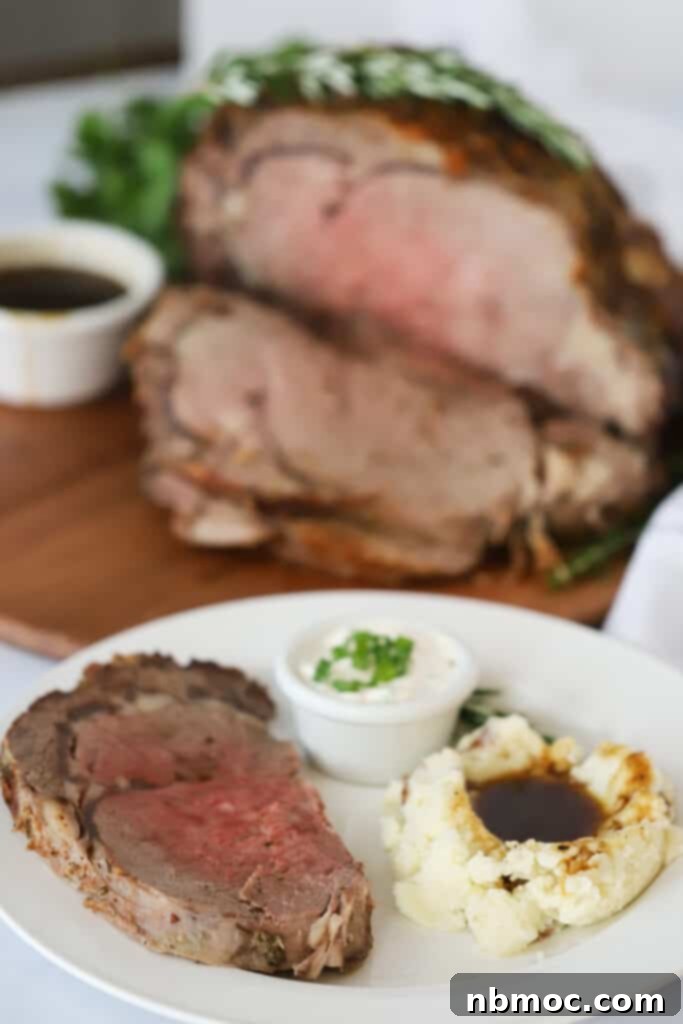 A white dinner plate with perfectly sliced Prime Rib, creamy mashed potatoes, and a side of homemade horseradish sauce, showcasing a classic holiday dinner spread.