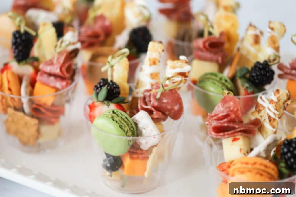 Beautifully arranged individual charcuterie cups on a serving platter, featuring meats, cheeses, fruits, and crackers. Ideal for easy party appetizers.