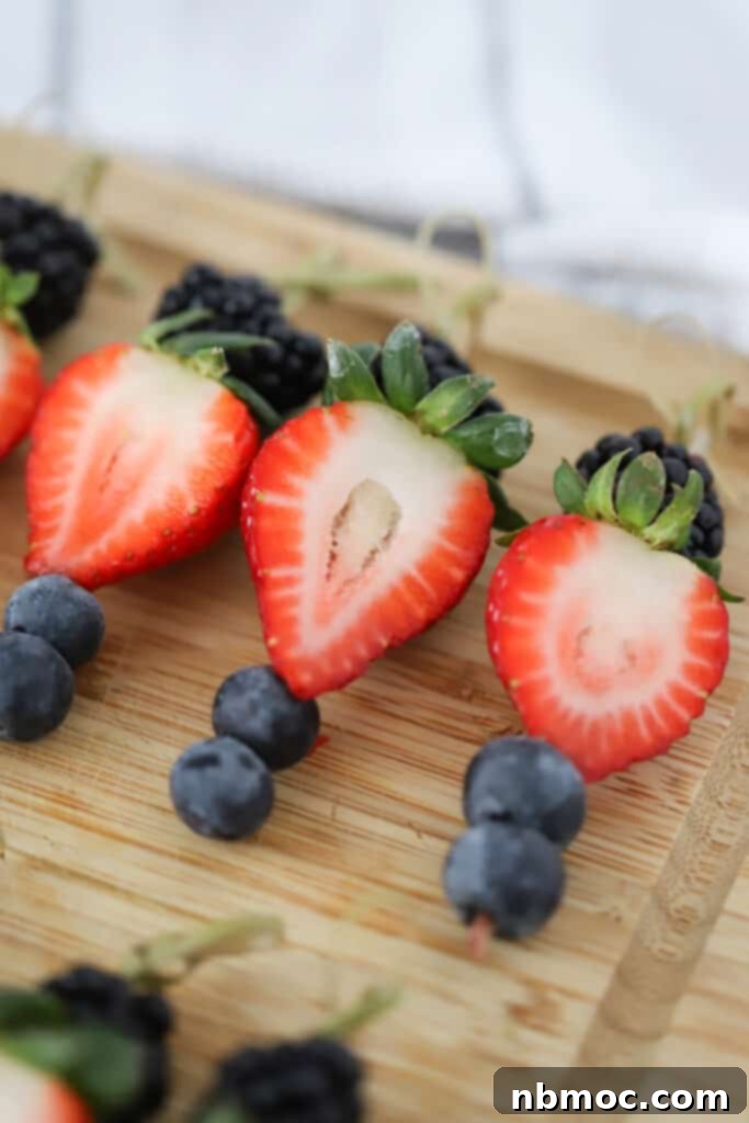 Bamboo toothpicks with fresh berries arranged on a cutting board, ready for individual charcuterie cups.
