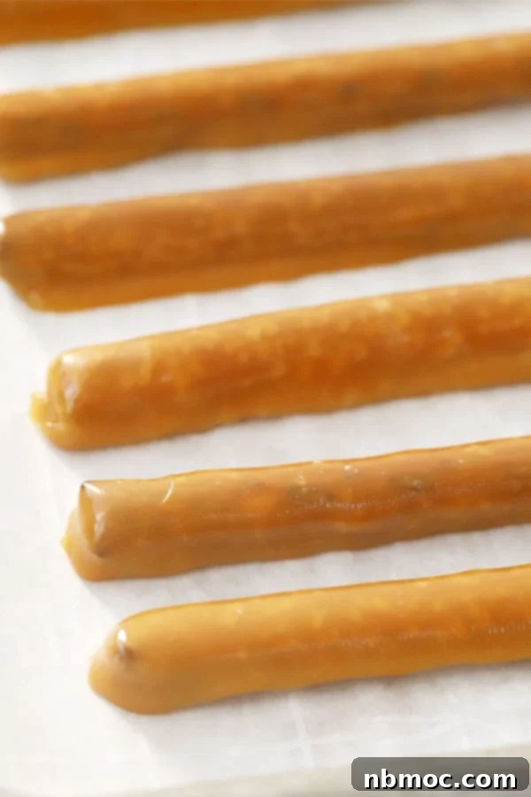 caramel covered pretzel rods on parchment paper