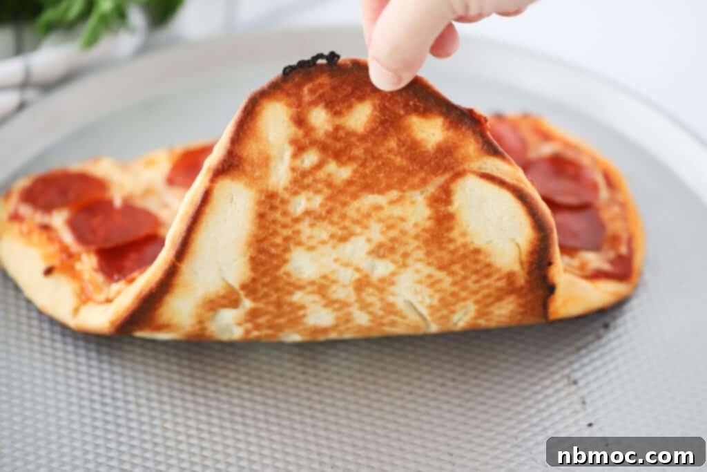 Heartwarming Pizza 5 A hand holding up a baked pizza to check the bottom. valentines pizza recipe. Shape pizza. Heart pizza.