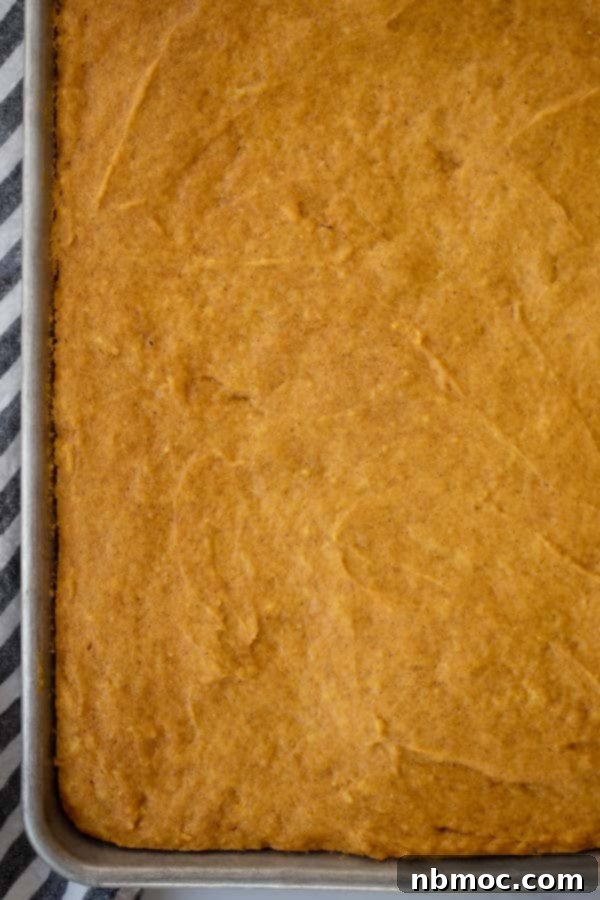 Harvest Pumpkin Spice Squares 3 A golden-brown baked pumpkin cake, cooled and waiting for its luscious cream cheese frosting before being cut into bars.