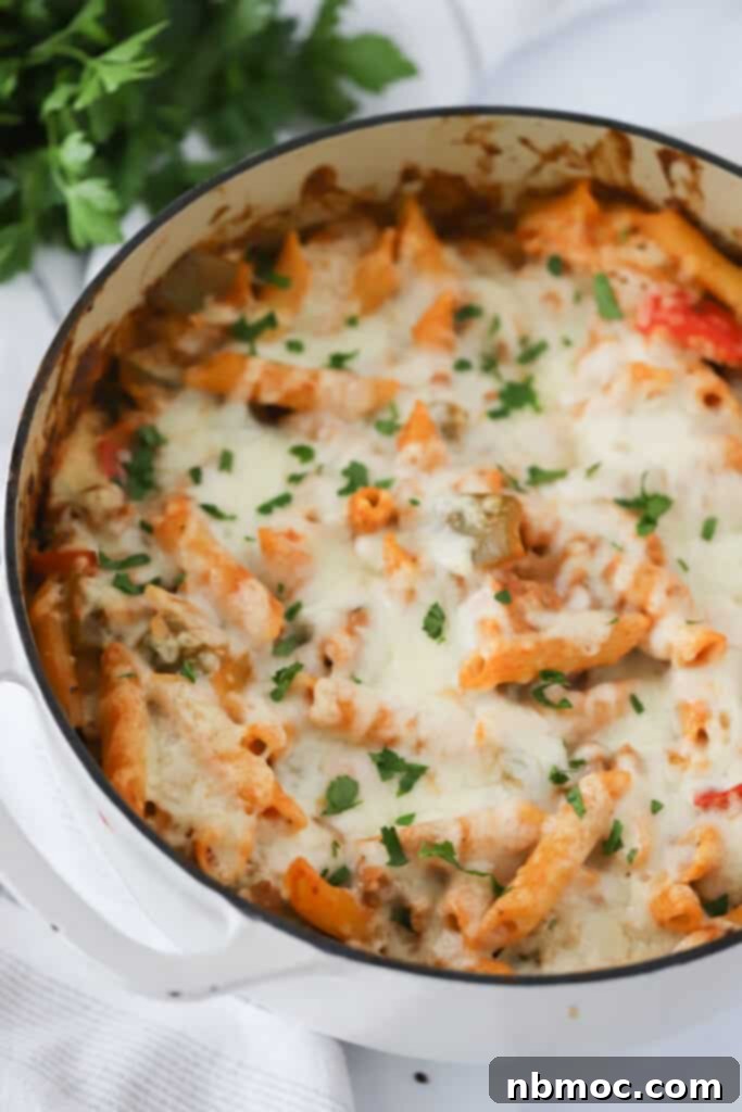 Italian Peppers and Sausage Pasta topped with melted mozzarella cheese in a dutch oven. 