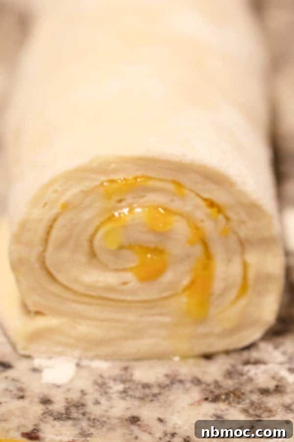 Orange rolls with a vibrant orange filling, rolled up tightly and ready to be sliced for baking.