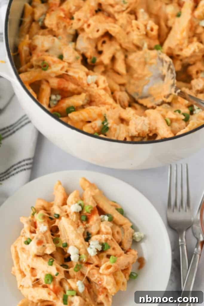 Fiery Buffalo Chicken Pasta 6 A serving of Buffalo Chicken Pasta being scooped from a Dutch oven onto a plate, showcasing its rich and appealing texture.