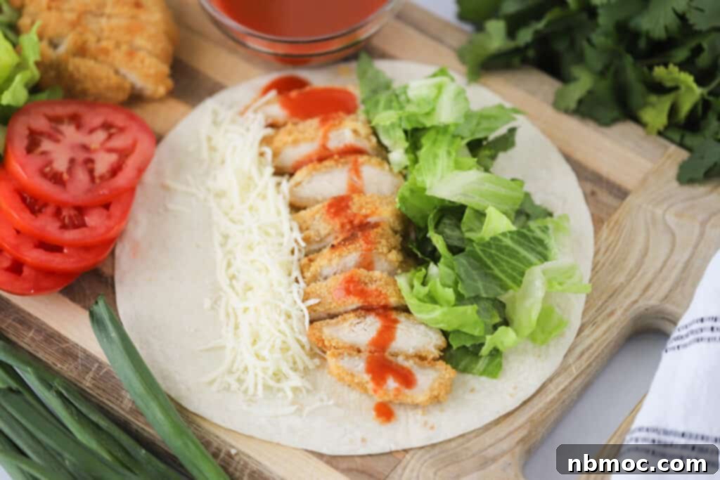 Zesty Buffalo Chicken Roll-Up 3 A tortilla laying flat with chicken, cheese, and lettuce ready to be turned into a buffalo chicken wrap. Buffalo chicken wraps recipe.