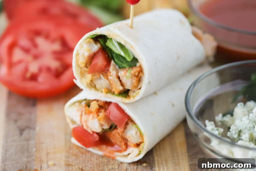 Zesty Buffalo Chicken Roll-Up 4 A buffalo chicken wrap sliced in half on a cutting board; crispy buffalo chicken wrap. Buffalo wrap.