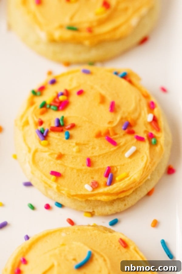Delightful Orange Creamsicle Cookies generously topped with smooth orange frosting and vibrant rainbow sprinkles, ready to be enjoyed.
