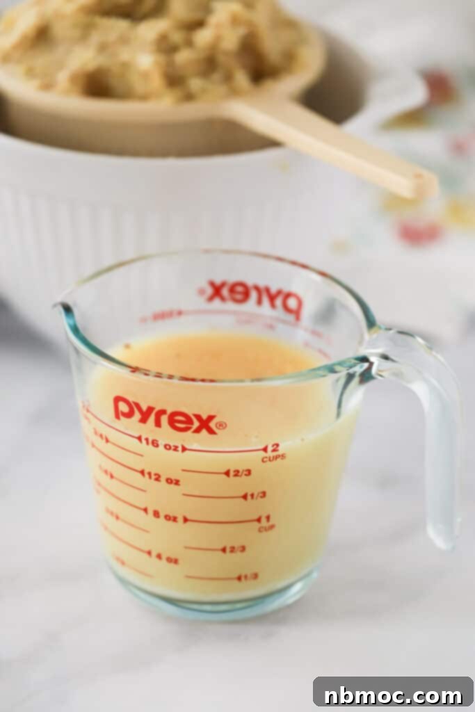 A glass measuring cup full of lemon and ginger juice for making a honey lemon ginger drink.