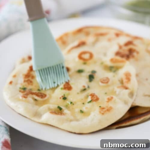 A close-up of a single piece of fresh homemade naan bread, perfectly golden and soft, with a hint of garlic butter.