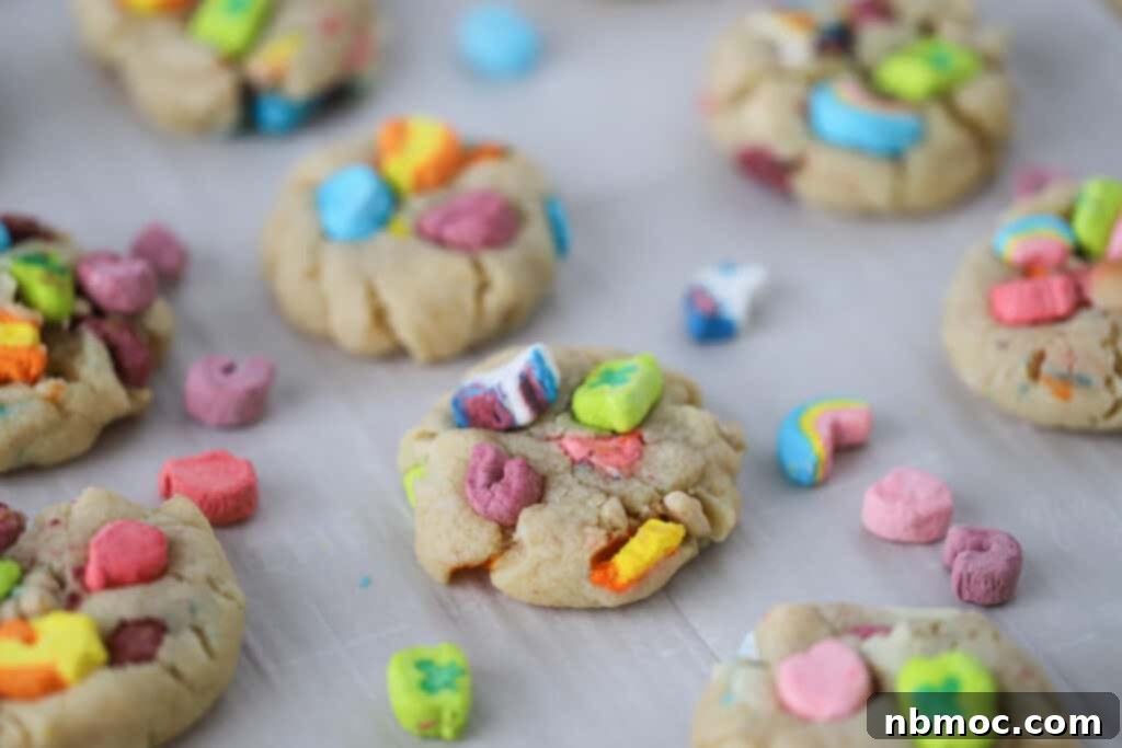 Freshly baked Lucky Charms Cookies cooling on a parchment-lined baking sheet, showcasing vibrant marshmallows and golden edges. A magically delicious dessert for any occasion.