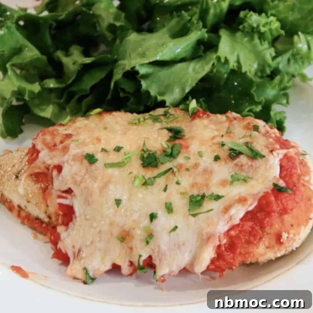 oven baked chicken parmesan recipe on a plate with salad