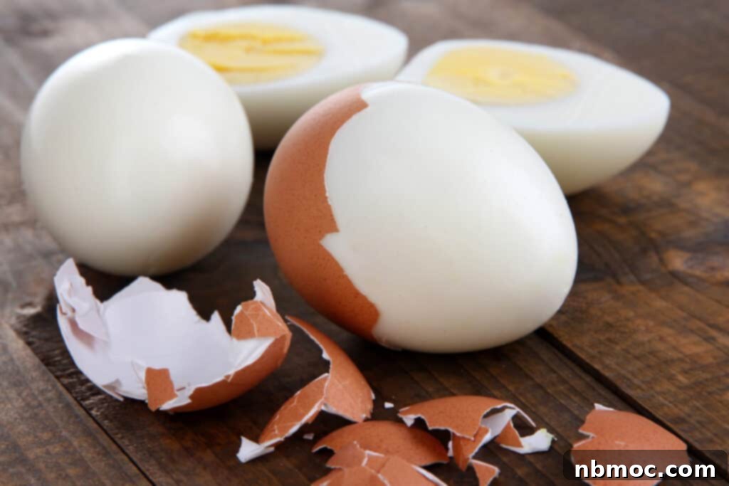 A hard boiled egg being peeled effortlessly, showcasing the easy peeling achieved with the baking soda method. Perfect hard boiled eggs that are a joy to peel.