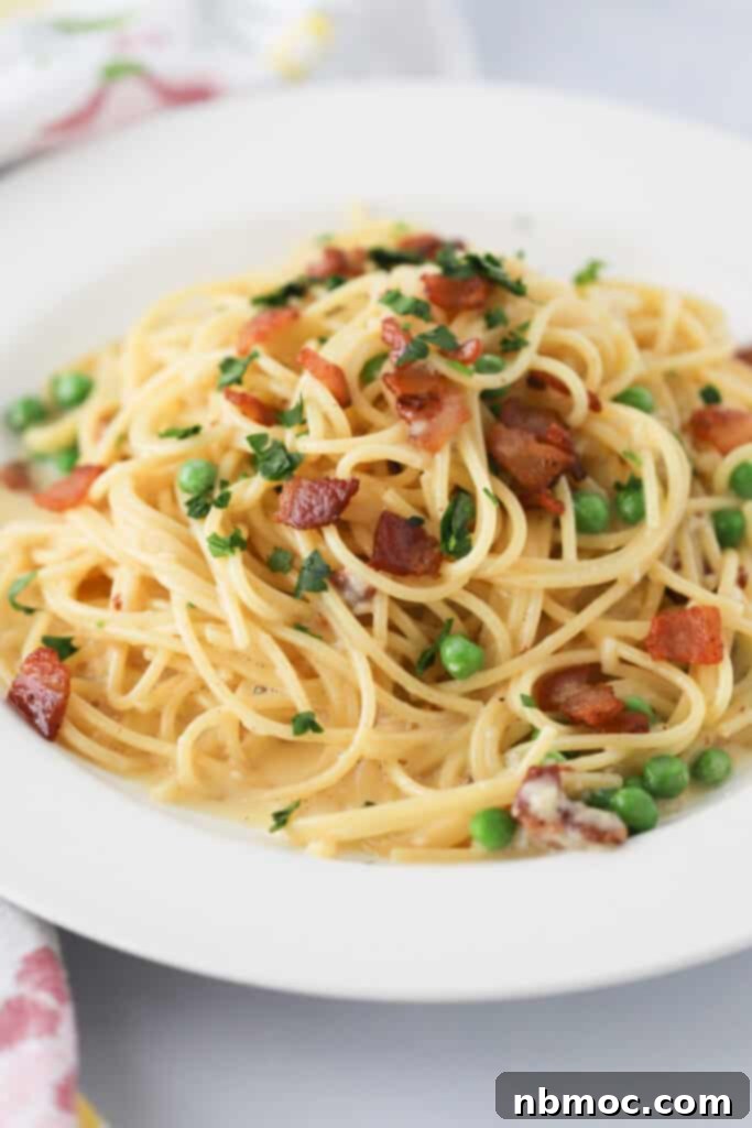 A plate full of easy Spaghetti Carbonara topped with bacon and peas.