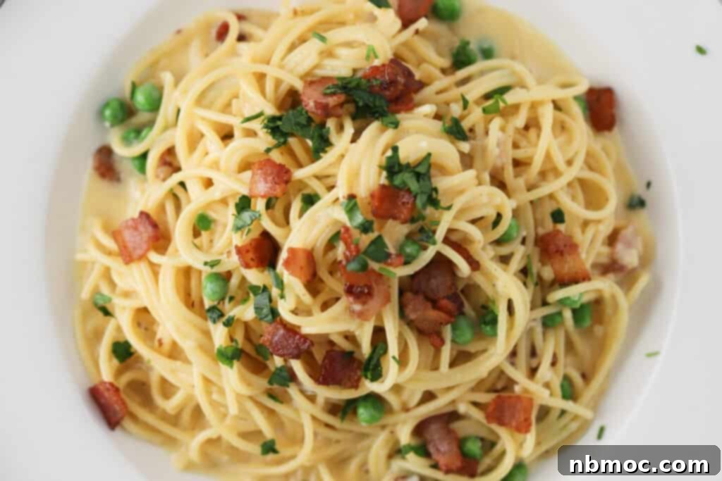 A bowl full of Spaghetti alla Carbonara topped with parsley, bacon, and peas. 